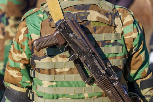 Automatic rifle without a magazine on the back of a military man. Background with selective focus and copy space for text