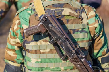 Bir askerin sırtında şarjörü olmayan otomatik bir tüfek. Seçici odaklı arkaplan ve metin için alanı kopyala