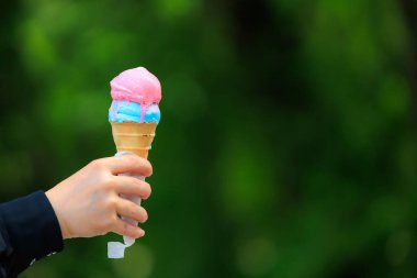Bulanık yeşil park arka planında dondurmalı waffle külahı. Metin için seçici odak ve kopyalama alanı