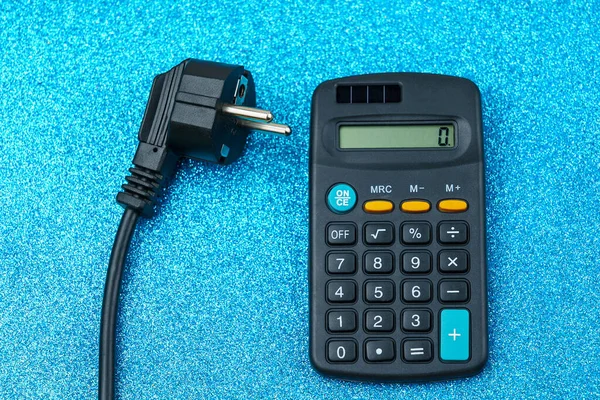 Elektrik kablosunun fişi hesap makinesinin yanında duruyor. Enerji krizi ve elektrik enflasyonu kavramı. Artan elektrik fiyatları. Metin için alanı kopyala