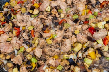 Uluslararası sokak yemekleri festivalinde et ve sebzeleri büyük bir kızartma tavasında satılığa çıkar. Özenle seçilmiş bir arka plan. Geleneksel festival mutfağı