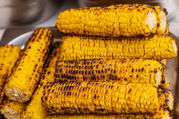 Close up of grilled corn for sale at the international street food festival, selective focus. Background. Traditional festive cuisine