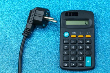 Elektrik kablosunun fişi hesap makinesinin yanında duruyor. Enerji krizi ve elektrik enflasyonu kavramı. Artan elektrik fiyatları. Metin için alanı kopyala