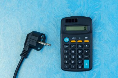 Elektrik kablosunun fişi hesap makinesinin yanında duruyor. Enerji krizi ve elektrik enflasyonu kavramı. Artan elektrik fiyatları. Metin için alanı kopyala