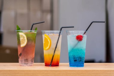 Uluslararası sokak yemekleri festivalinde şeffaf, tek kullanımlık bardaklarda pipetlerle serinletici üç meyve kokteylini kapatıyoruz. Kopyalama alanı olan arkaplan