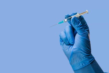 Doktorlar ameliyat eldivenlerini teslim ederken klasik bir sembolik mavi arka plan üzerinde şırınga tutuyorlar.