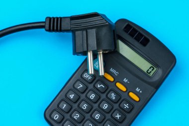 Elektrik kablosunun fişi hesap makinesinin yanında duruyor. Enerji krizi ve elektrik enflasyonu kavramı. Artan elektrik fiyatları. Metin için alanı kopyala