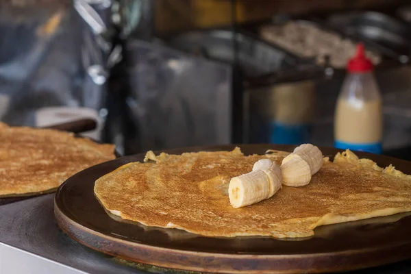 Close up of fried pancakes with banana for sale at the international street food festival. Background with selective focus. Traditional festive cuisine