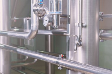 Bira fabrikasında bira musluğu. Arka planda paslanmaz çelik borular var.