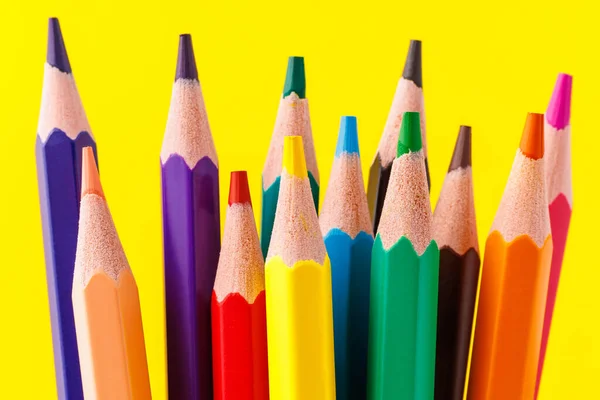 Colored pencils close-up with selective focus on the stylus and a blurred yellow background. Copy space