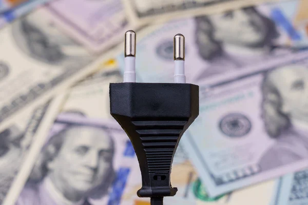 Electric cord plug and dollars on a blurred background, selective focus. The concept of the energy crisis and electricity inflation. Rising electricity prices. Copy space.