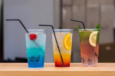 Uluslararası sokak yemekleri festivalinde şeffaf, tek kullanımlık bardaklarda pipetlerle serinletici üç meyve kokteylini kapatıyoruz. Kopyalama alanı olan arkaplan