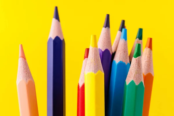 Colored pencils close-up with selective focus on the stylus and a blurred yellow background. Copy space