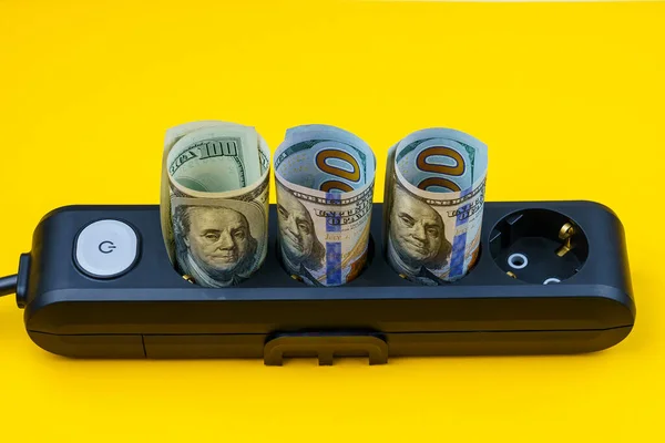 Rolled dollar bills in power strip sockets. The concept of the energy crisis and electricity inflation. Rising electricity prices. Copy space for text.