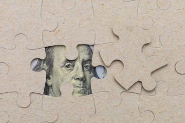 Kayıp yapboz parçası ve çerçevelenmiş Amerikan doları. Metin için kopyalama alanı olan arkaplan