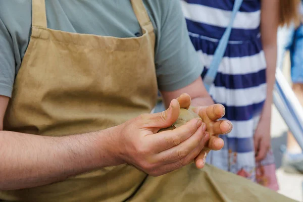 The potter kneads the clay. Close-up hands. Background with copy space for text