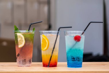 Uluslararası sokak yemekleri festivalinde şeffaf, tek kullanımlık bardaklarda pipetlerle serinletici üç meyve kokteylini kapatıyoruz. Kopyalama alanı olan arkaplan