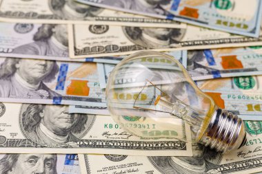 Dolar banknotları ya da banknotların bulanık arka planında klasik elektrik ampulü. Enerji krizi ve elektrik enflasyonu kavramı. Elektrik fiyatlarında artış. Metin için alanı kopyala.
