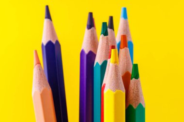 Renkli kalemler, stil üzerine özenli odaklanmış ve bulanık sarı bir arka plan. Boşluğu kopyala