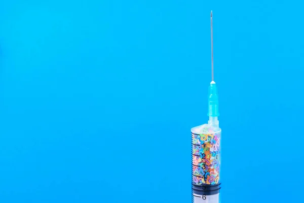 A classic disposable syringe filled with symbolic hearts. Love concept. Background with copy space for text. Blue medical backdrop.