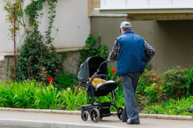 Bebek arabası olan yetişkin bir adam bir çocukla yürür. Metin için kopyalama alanı olan arkaplan