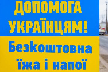 The inscription in Ukrainian Help Ukrainians free food and drinks. Ukrainian flag background with selective focus and copy space