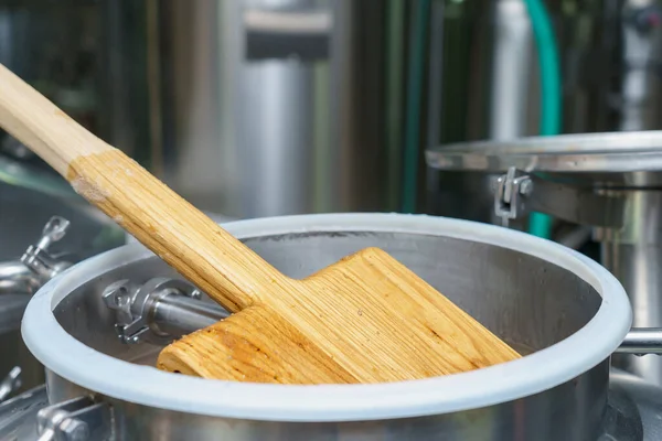 Wooden stirrer in the process of brewing beer. Background with selective focus and copy space for text