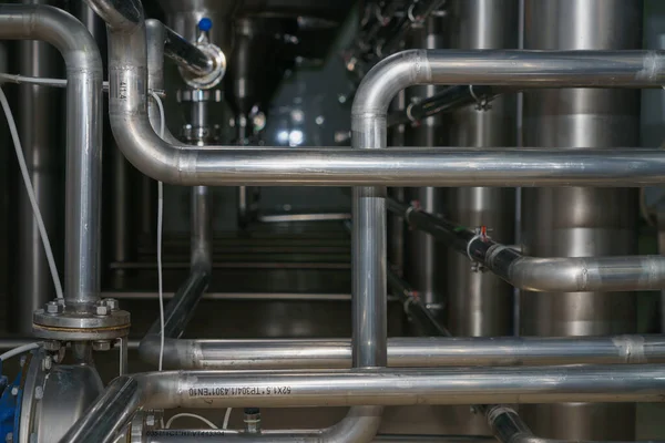 A stainless steel pipe system in the food industry at a brewery in the process of brewing beer. Background with selective focus and copy space for text