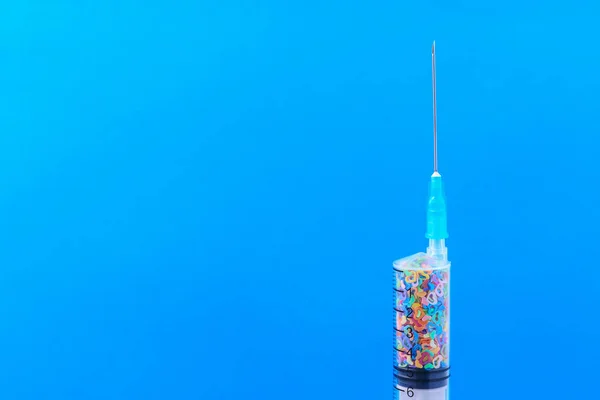 A classic disposable syringe filled with symbolic hearts. Love concept. Background with copy space for text. Blue medical backdrop.