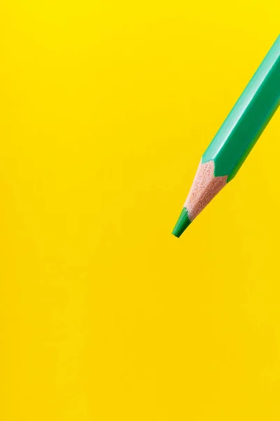 Colored pencil close-up with selective focus on the stylus and a blurred yellow background. Copy space for text.