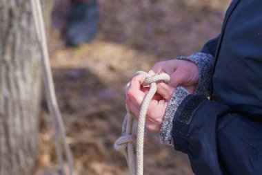 Bir turistin elleri, seçici bir odak noktasıyla ipte düğüm atıyor. Metin için kopyalama alanı olan arkaplan