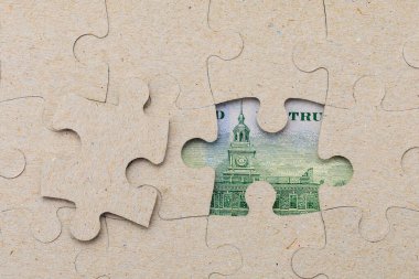 Kayıp yapboz parçası ve çerçevelenmiş Amerikan doları. Metin için kopyalama alanı olan arkaplan