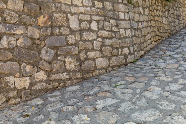 Stone wall and stone road or pavement in the architecture of the old city. Background or backdrop