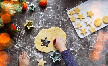 3-4 yaşlarında tatlı bir kız kendi Noel kurabiyelerini yapıyor. Tatillerde evde aile tatili. Un ve hamur. Yılbaşı ve Noel. Elinde hamuru tutan çocuk