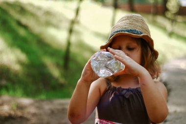 The child drinks water from a plastic bottle. Baby 5 years old.