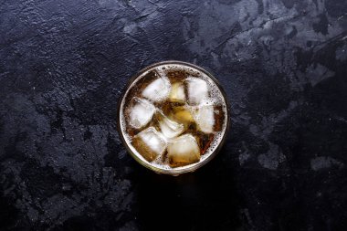 Glass with lemonade and ice. Top view. Copy space. A glass of beer on a dark concrete background.