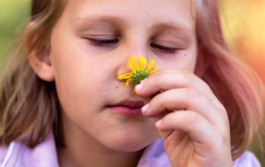 Çocuk bir çiçek kokusu alıyor. Küçük kız parkta dinleniyor. Uzayı kopyala Yakından güzel bir kızın portresi..