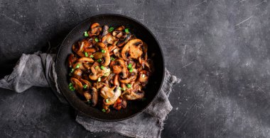 Kızarmış mantarlı ve soğanlı, ahşap arka planda, üst tarafta.