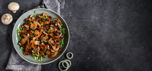 Kızarmış mantarlı ve soğanlı, ahşap arka planda, üst tarafta.