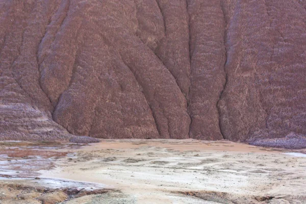 Kil ve endüstriyel atıktan oluşan parlak, kırmızı bir dağın eteğinde. Sanayi atıkları.