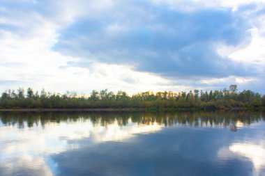 Nehrin su yüzeyinde ağaçların ve bulutlu gökyüzünün yansıması. Sonbahar manzarası.