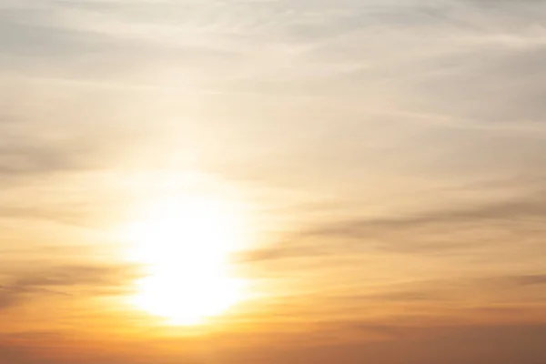Parlak, sarı güneş günbatımında yüksek bulutların arasından parlar. Akşam gökyüzünde bir ışık huzmesi.