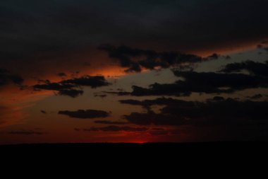 Kızıl güneş ufuktan battı ve yüksek bulutlar akşam gökyüzünü kapladı. Güzel gün batımı.