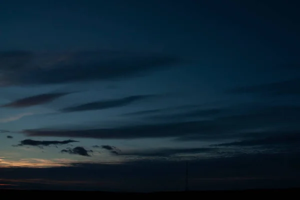 Kızıl güneş ufuktan battı. Bulutlu mavi gökyüzünde güzel bir gün batımı. Güneşin ufukta bıraktığı iz.