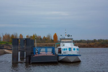 Sonbahar bulutlu bir günde rıhtıma demirlemiş beyaz bir gemi. Nehirde beyaz bir tekne.