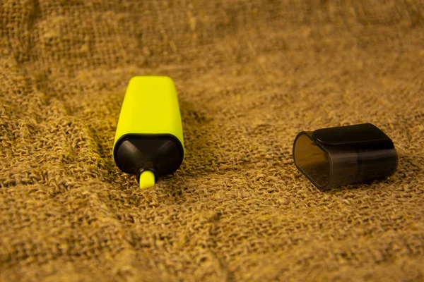 Sarı fosforlu kalem gri bir kumaşın üzerinde. Sarı çuval bezi üzerine kırtasiye..