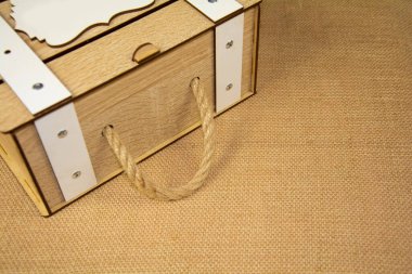 Bej renkli çuval bezi arka planında ip sapı olan gri bir vintage kutu. Antika, ahşap ürün masanın üstünde..