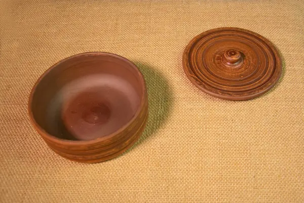 Boş bir kil vazo ve çuval beziyle kaplı bir masanın kapağı. Masadaki kahverengi çömlek.