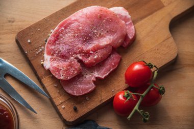 Izgara için çiğ biftek eti. Ahşap bir masanın üzerindeki malzemeler..