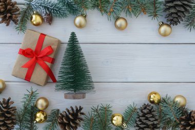 Oyuncak noel ağacının en üst görüntüsü ve beyaz ahşap arka planda çam ağacı dalları ve koni ile çerçevelenmiş paketlenmiş hediye kutusu, kopyalama alanı. Noel katkısı                              